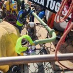 photo taken from above of a welder welding a flange on a green pipe on the back deck of a work boat